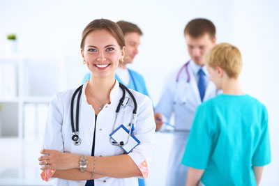 Four Medical Professional ( two females and two males ) standing around talking and smiling.